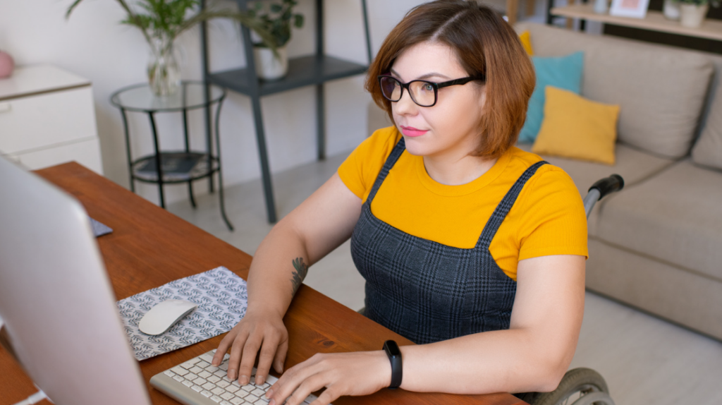 Decorative image of a person using a wheelchair who is also currently engaged in studying on a computer